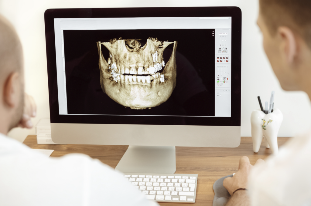 Two doctors discuss the scanned digital image of a patient’s teeth
